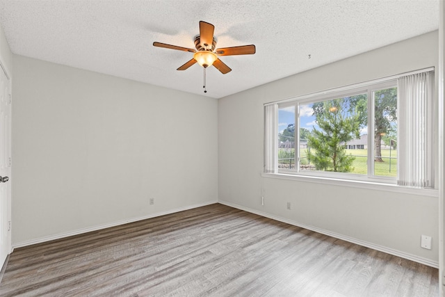 empty room with a textured ceiling, baseboards, a ceiling fan, and wood finished floors