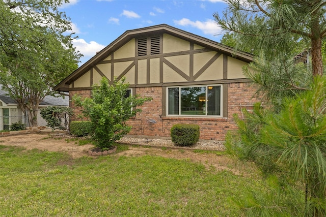 view of home's exterior with stucco siding, a yard, and brick siding