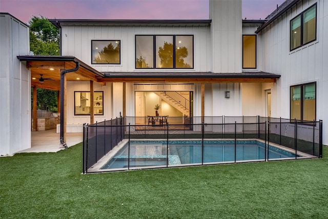 back of property with a fenced in pool, a lawn, and fence