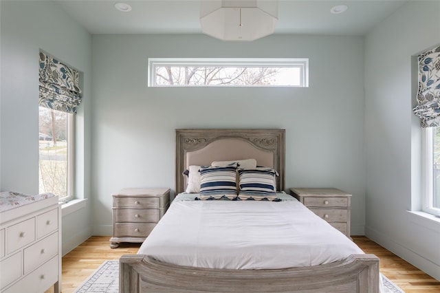 bedroom with baseboards, multiple windows, and light wood-type flooring