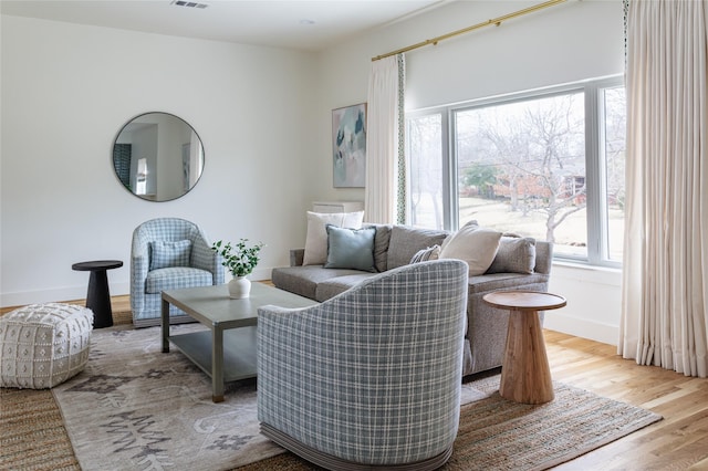 sitting room with baseboards, visible vents, plenty of natural light, and light wood finished floors
