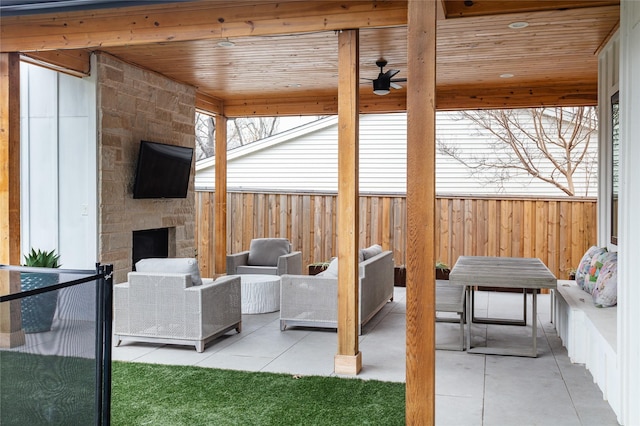 view of patio / terrace with ceiling fan, a fenced backyard, and an outdoor living space with a fireplace
