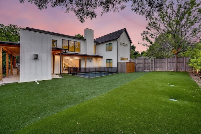 back of property with a fenced backyard, a fenced in pool, a chimney, a patio, and a yard