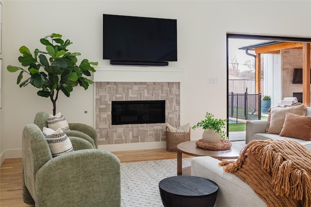 living room with baseboards, a glass covered fireplace, and wood finished floors