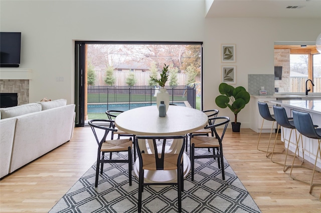 dining space with visible vents, a glass covered fireplace, and light wood finished floors