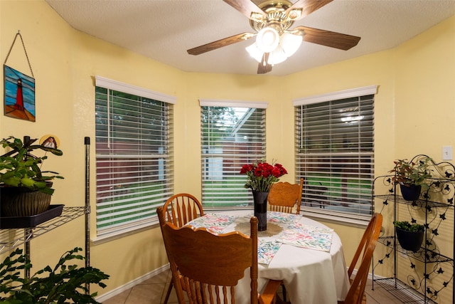 tiled dining room featuring a textured ceiling, ceiling fan, and baseboards