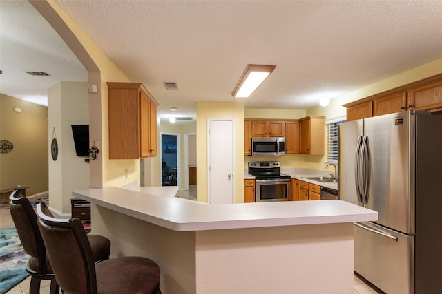 kitchen featuring a sink, light countertops, stainless steel appliances, a peninsula, and visible vents