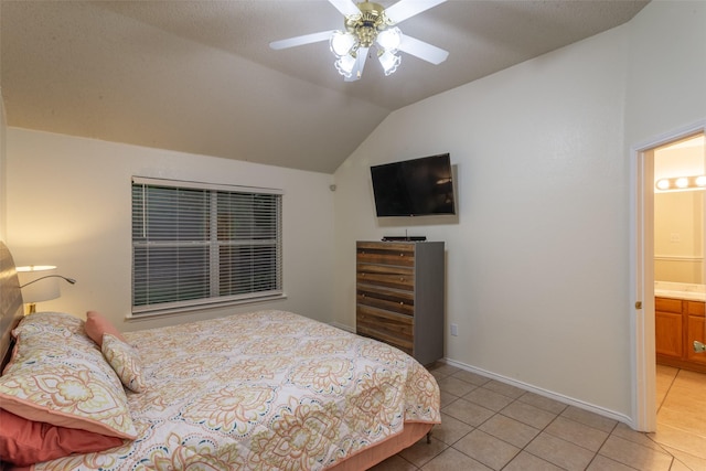 bedroom with ceiling fan, vaulted ceiling, baseboards, ensuite bath, and light tile patterned flooring