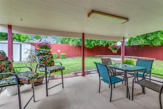 view of patio / terrace with a fenced backyard, outdoor dining space, an outdoor structure, and a shed