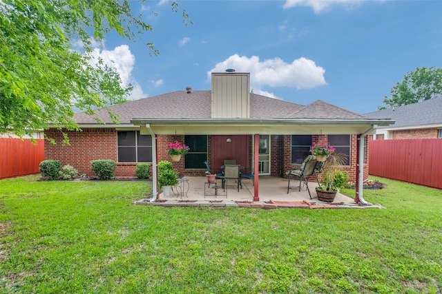 back of house featuring a yard, brick siding, and a fenced backyard