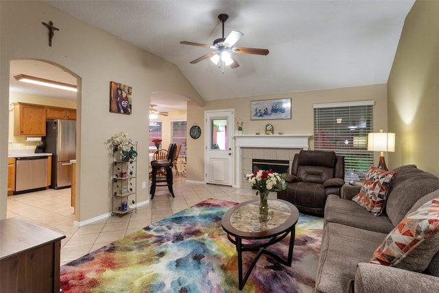 living area featuring arched walkways, ceiling fan, light tile patterned flooring, and lofted ceiling