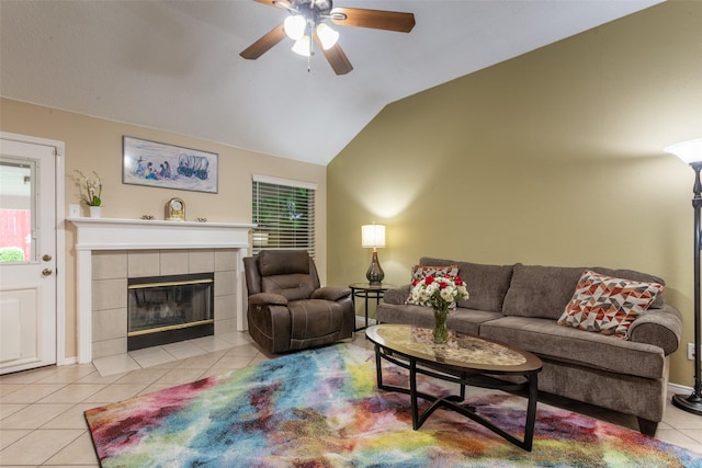 living area with ceiling fan, light tile patterned floors, vaulted ceiling, and a tile fireplace