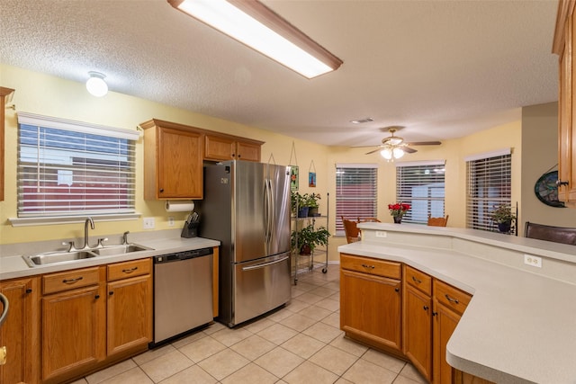 kitchen featuring a ceiling fan, appliances with stainless steel finishes, a sink, light tile patterned floors, and light countertops