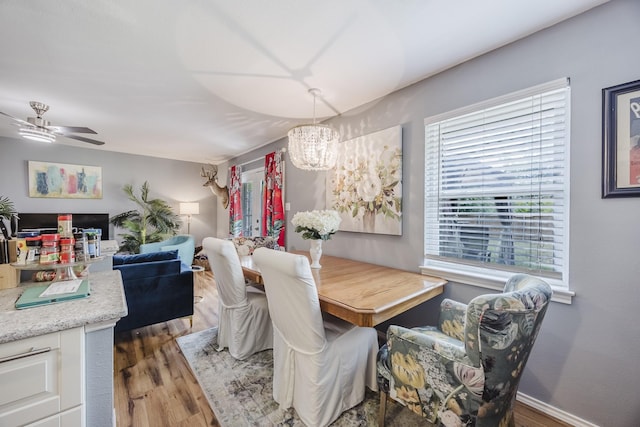 dining area featuring wood finished floors, a chandelier, a ceiling fan, and baseboards