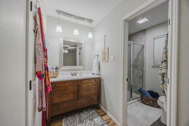 full bath featuring a shower stall, toilet, vanity, and wood finished floors