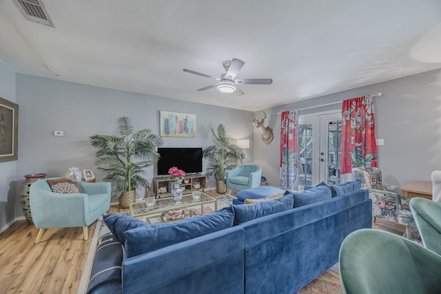 living area featuring french doors, wood finished floors, a ceiling fan, and baseboards