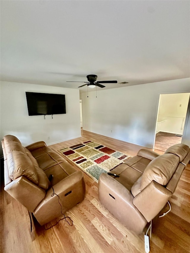 living room featuring a ceiling fan, baseboards, visible vents, and wood finished floors