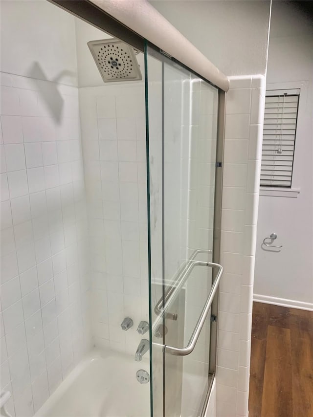 full bath featuring baseboards, enclosed tub / shower combo, and wood finished floors