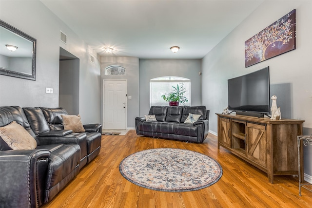 living area with baseboards, visible vents, and wood finished floors