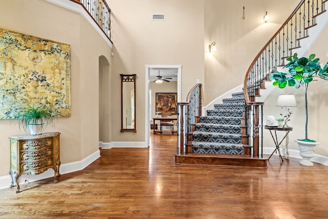 entryway with a high ceiling, stairs, a ceiling fan, wood finished floors, and baseboards