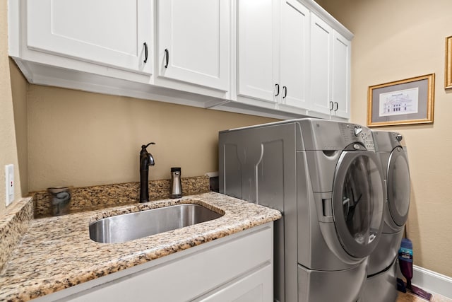 clothes washing area with cabinet space, separate washer and dryer, and baseboards
