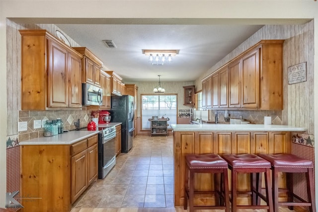 270 Alexandra Dr, Tuscola, TX 79562 - kitchen featuring range with electric stovetop, stainless steel microwave, a peninsula, and brown cabinets
