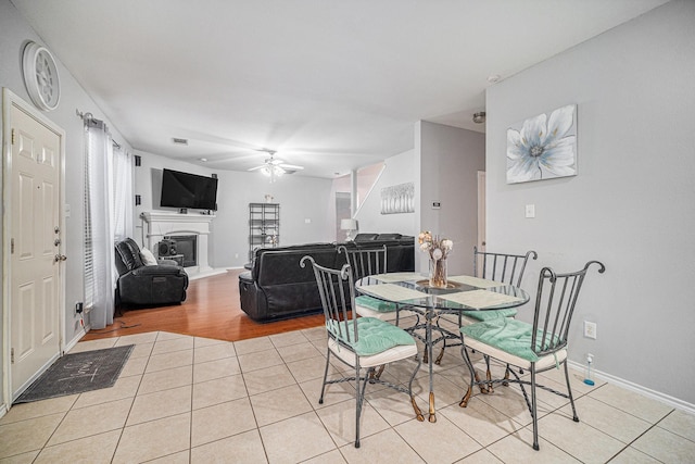 2100 Leandra Ln, Fort Worth, TX 76131 - dining area featuring light tile patterned floors, baseboards, ceiling fan, and a glass covered fireplace