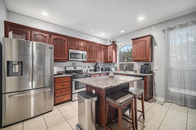 2100 Leandra Ln, Fort Worth, TX 76131 - kitchen featuring light tile patterned floors, appliances with stainless steel finishes, a center island, and light stone counters