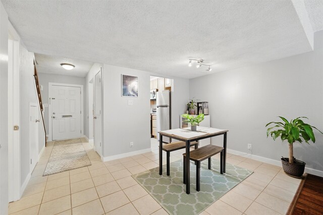 dining room with baseboards, a textured ceiling, and light tile patterned floors