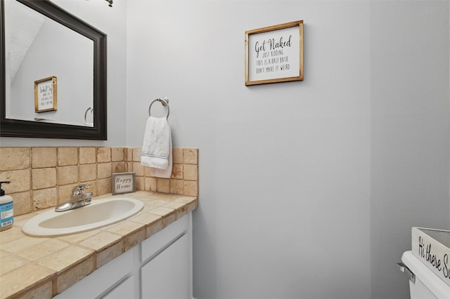 bathroom featuring vanity, decorative backsplash, and toilet