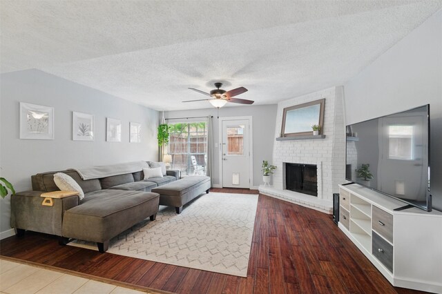 living room with wood-type flooring, a fireplace, baseboards, ceiling fan, and a textured ceiling