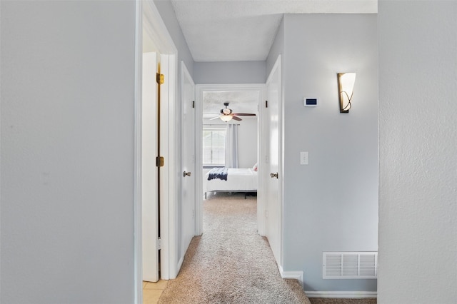 hallway featuring visible vents and light colored carpet