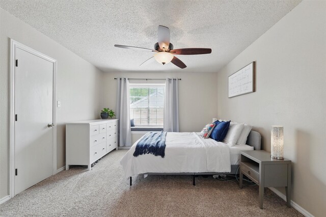 bedroom with baseboards, a textured ceiling, ceiling fan, and light carpet