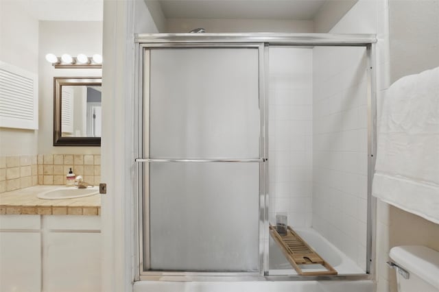 full bathroom with vanity, a shower with shower door, toilet, and tasteful backsplash