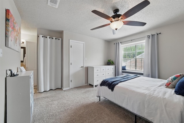 bedroom featuring light colored carpet, a textured ceiling, a ceiling fan, light tile patterned floors, and visible vents