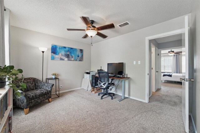 carpeted home office featuring visible vents, a textured ceiling, baseboards, and ceiling fan