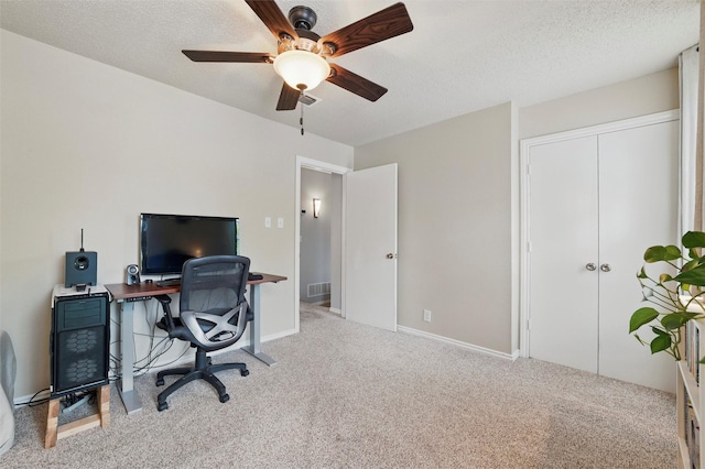 carpeted home office featuring a ceiling fan, a textured ceiling, and visible vents