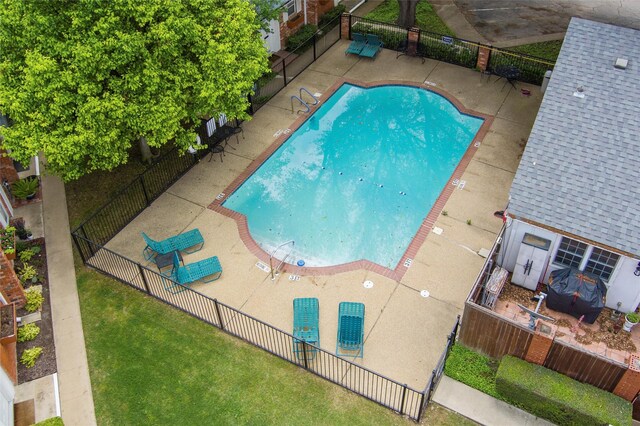 pool with a patio area, fence, and a yard