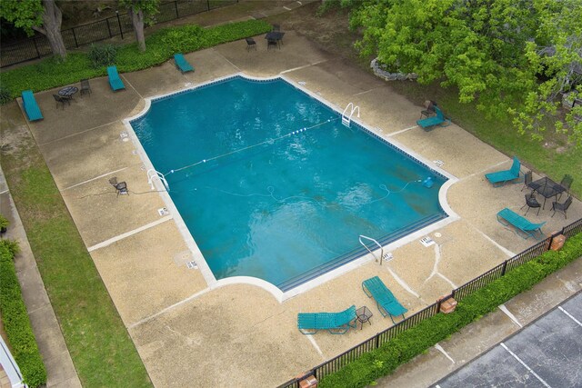 community pool with a patio area and fence