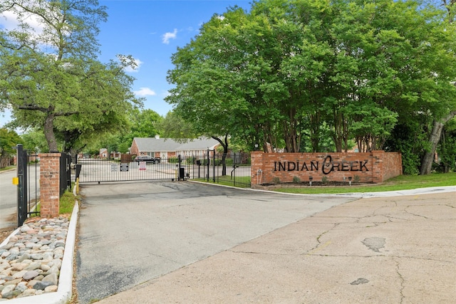 view of street with a gate, a gated entry, and curbs