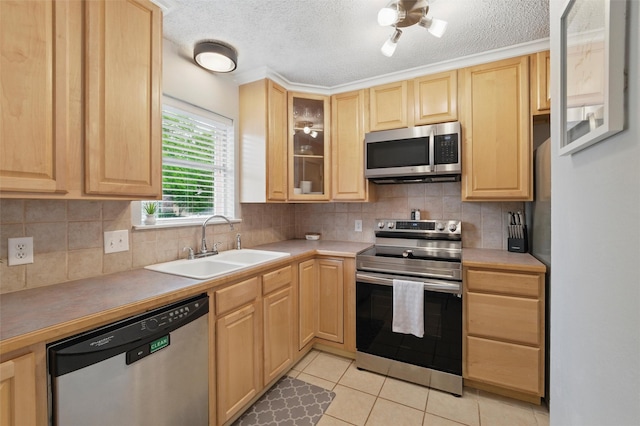 kitchen with light brown cabinetry, light tile patterned flooring, a sink, stainless steel appliances, and glass insert cabinets