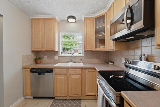 kitchen featuring light countertops, a sink, light brown cabinetry, and stainless steel appliances