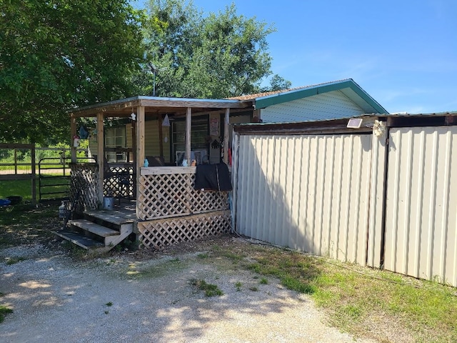 view of side of home with fence and covered porch