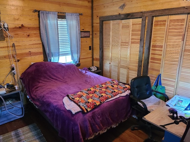 bedroom with multiple closets, wood walls, and wood finished floors
