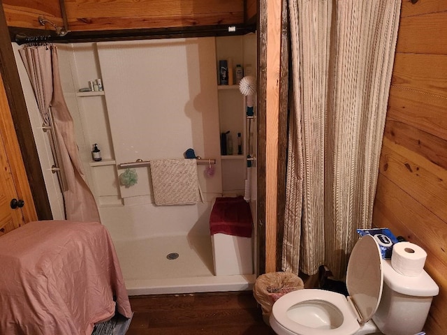 bathroom featuring a shower stall, toilet, and wood finished floors
