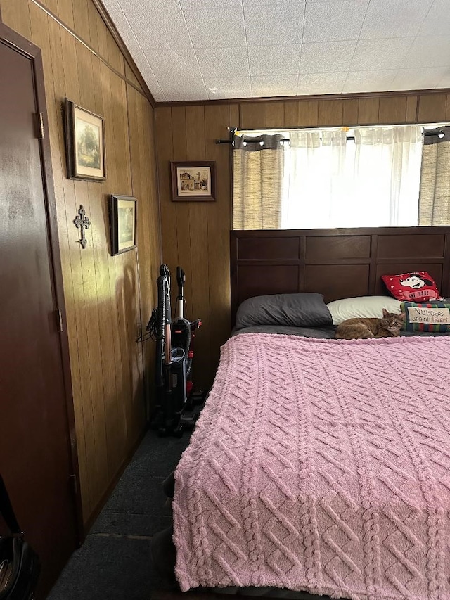 carpeted bedroom with wooden walls and vaulted ceiling