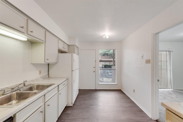 kitchen with light countertops, white cabinets, dark wood finished floors, and a sink
