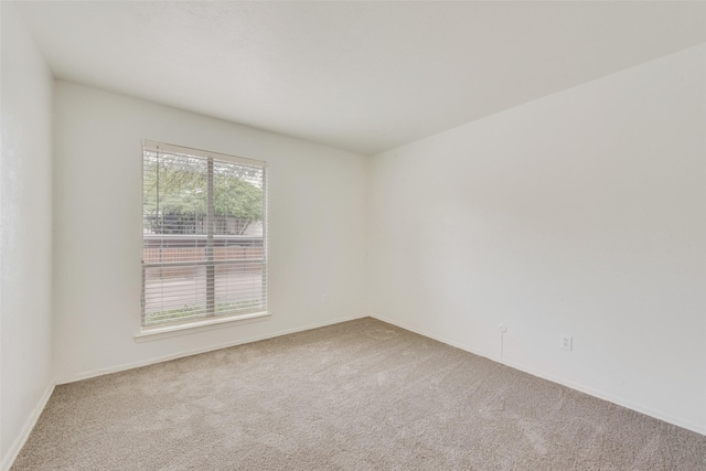 carpeted empty room featuring baseboards