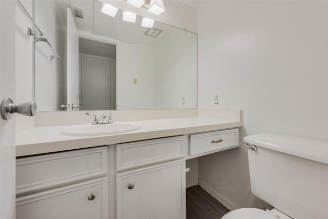 bathroom featuring toilet, baseboards, wood finished floors, and vanity