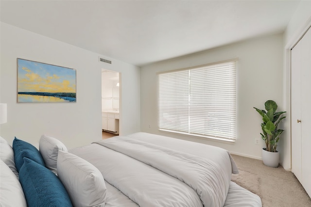 bedroom featuring light carpet, ensuite bathroom, and visible vents